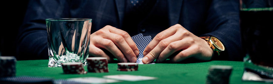 poker table showing chips, and cards in a mans hand